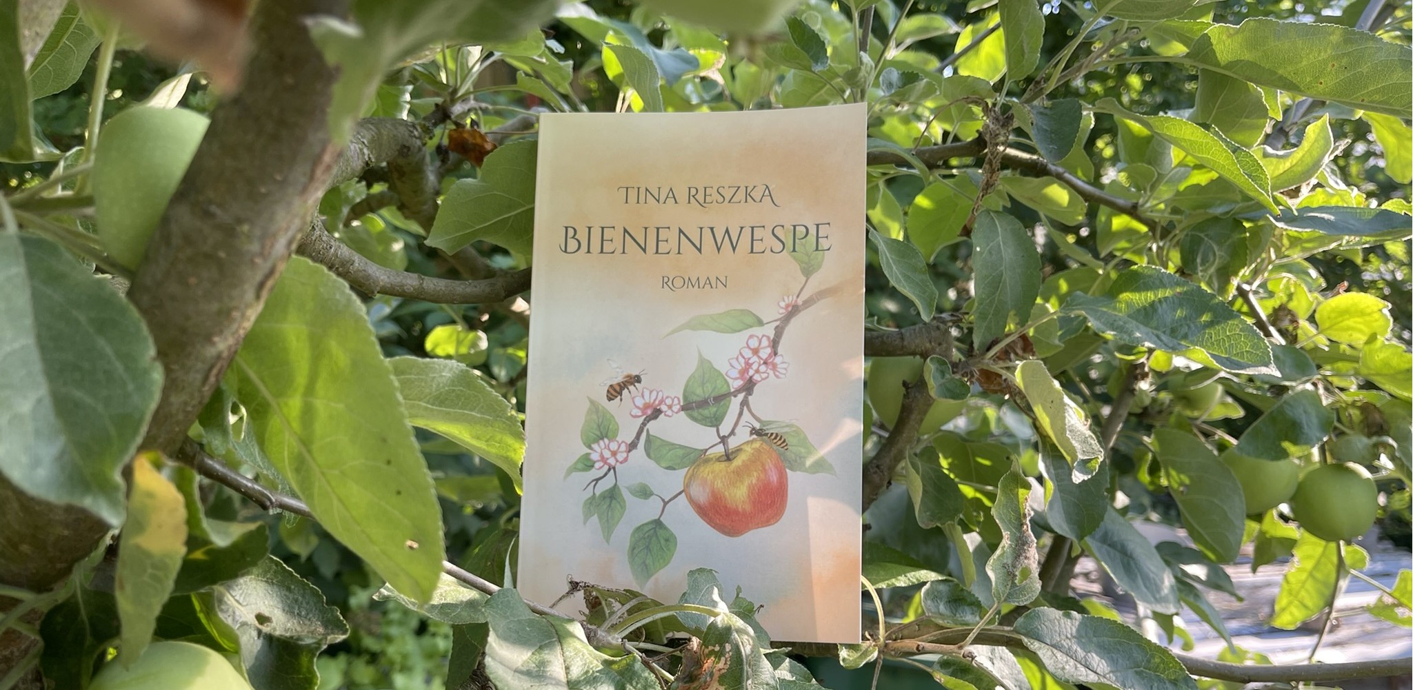 Das Buch „Bienenwespe“ hängt zwischen den Zweigen eines Apfelbaums